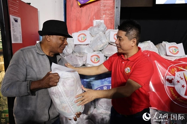 巴西中國(guó)浙江商會(huì)會(huì)長(zhǎng)鄭俠茂向社區(qū)居民轉(zhuǎn)交捐贈(zèng)物資。人民網(wǎng)記者 時(shí)元皓攝