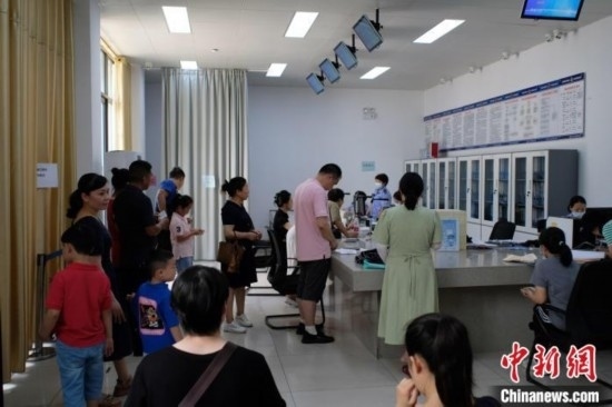 圖為在戶籍辦證廳內(nèi)排隊等待的家長和孩子。劉俊聰 攝