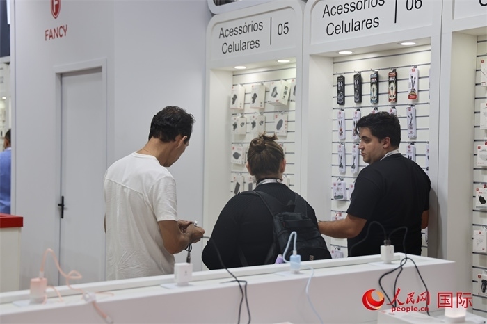 幾名參觀者在一個展臺前了解手機配件。（人民網(wǎng)記者 時元皓攝）