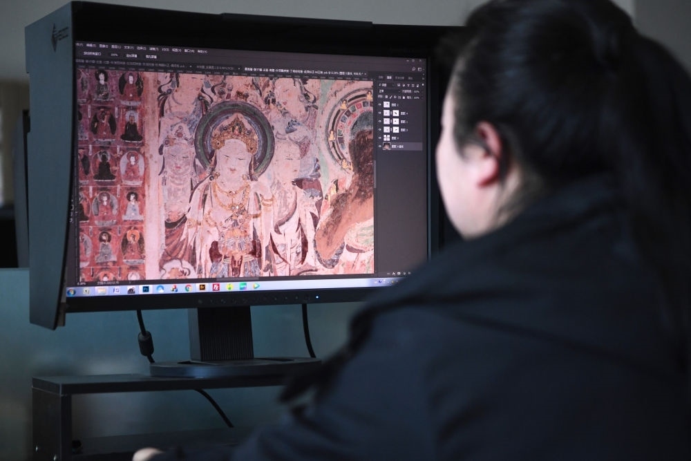 敦煌研究院文物數(shù)字化保護(hù)團(tuán)隊(duì)圖像處理人員年海麗在拼接壁畫(huà)圖像（2023年4月25日攝）。數(shù)字化探索為莫高窟的保護(hù)與傳承開(kāi)辟了全新路徑，數(shù)字技術(shù)讓敦煌文物走出洞窟，跨出國(guó)門，走向“永久保存、永續(xù)利用”。新華社記者 陳斌 攝