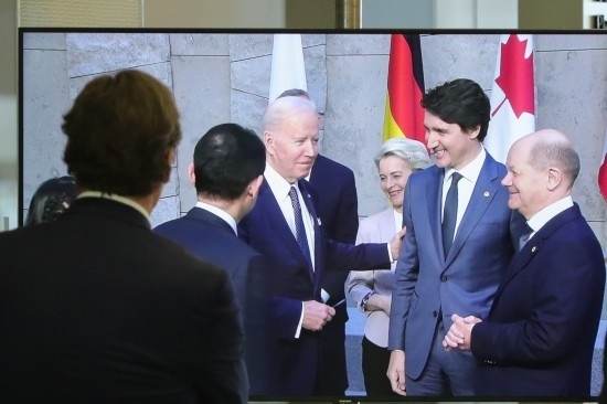 2022年3月24日，在比利時(shí)布魯塞爾的北約總部，一名男子觀看屏幕上美國(guó)總統(tǒng)拜登（右四）、歐盟委員會(huì)主席馮德萊恩（右三）、加拿大總理特魯多（右二）、德國(guó)總理朔爾茨（右一）出席七國(guó)集團(tuán)峰會(huì)合影儀式的畫(huà)面。新華社記者鄭煥松攝