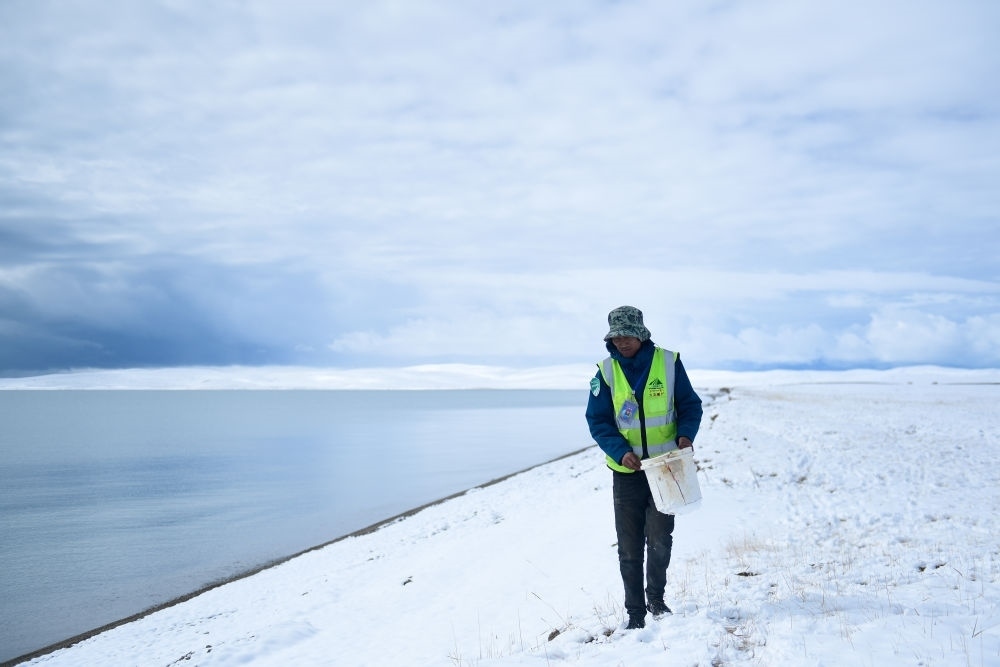 2021年10月20日，在青海省果洛藏族自治州瑪多縣扎陵湖鄉(xiāng)勒那村，三江源國(guó)家公園黃河源園區(qū)生態(tài)管護(hù)員在扎陵湖邊撿拾垃圾。新華社記者 張龍 攝