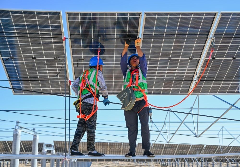 2023年7月22日，工人在位于內(nèi)蒙古杭錦旗庫(kù)布其沙漠億利生態(tài)示范區(qū)的蒙西基地庫(kù)布其200萬(wàn)千瓦光伏治沙項(xiàng)目工地安裝光伏板。新華社記者 劉磊 攝