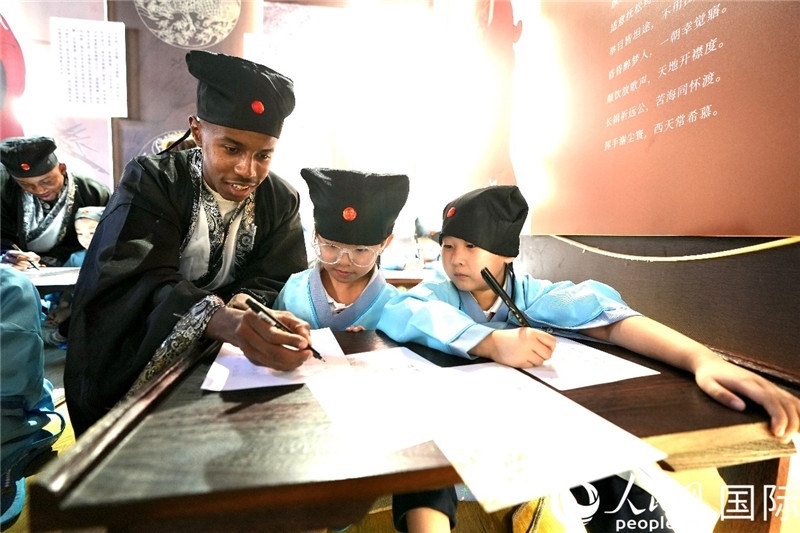 圖為選手與同學們一起寫書法。人民網 盧鵬宇攝