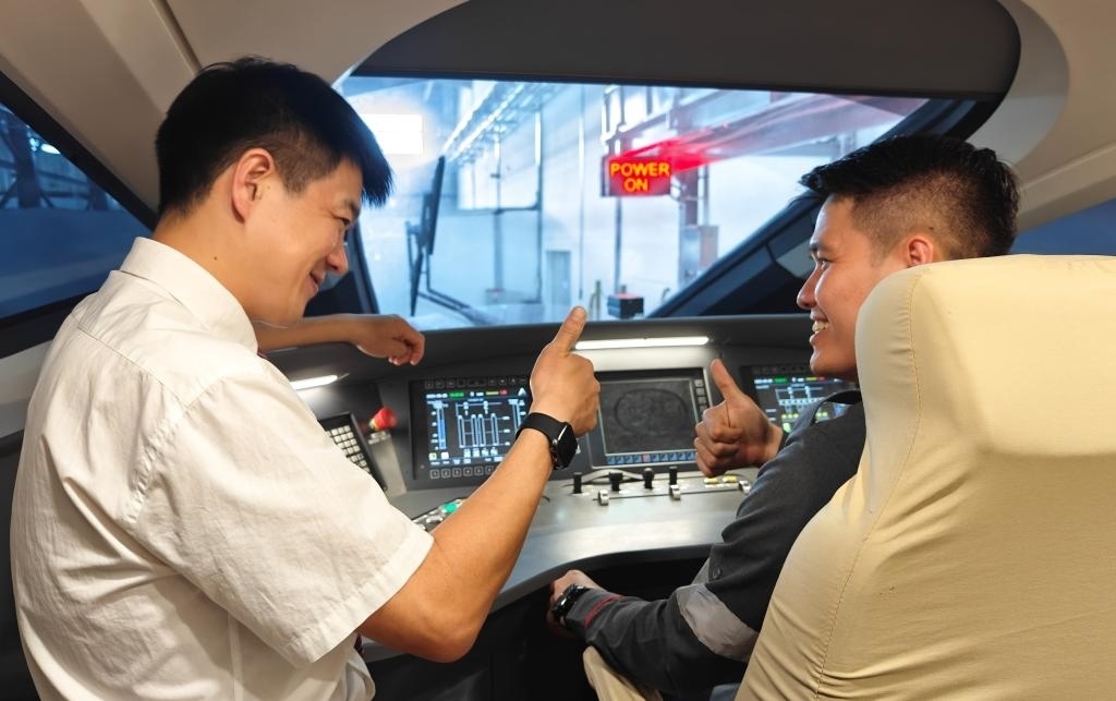 8月25日，在印度尼西亞萬隆的雅萬高鐵德卡魯爾動車所內(nèi)，中國師傅穆振（左）在向印尼火車司機(jī)塞蒂亞萬講解動車組出庫前的上電作業(yè)。