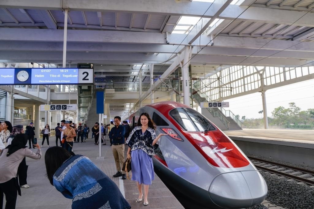10月17日，在印度尼西亞萬隆德卡魯爾站，乘客在站臺上和雅萬高鐵高速動車組列車合影。