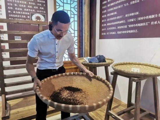 2023“一帶一路”媒體合作論壇聯(lián)合采訪團團員在非遺文化展示館體驗中藥炮制技藝。（本報記者 黃超攝）