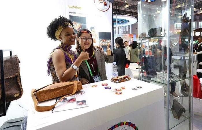 11月6日，一位參觀者（右）在第六屆進(jìn)博會(huì)國家展南非展臺(tái)試戴傳統(tǒng)首飾。