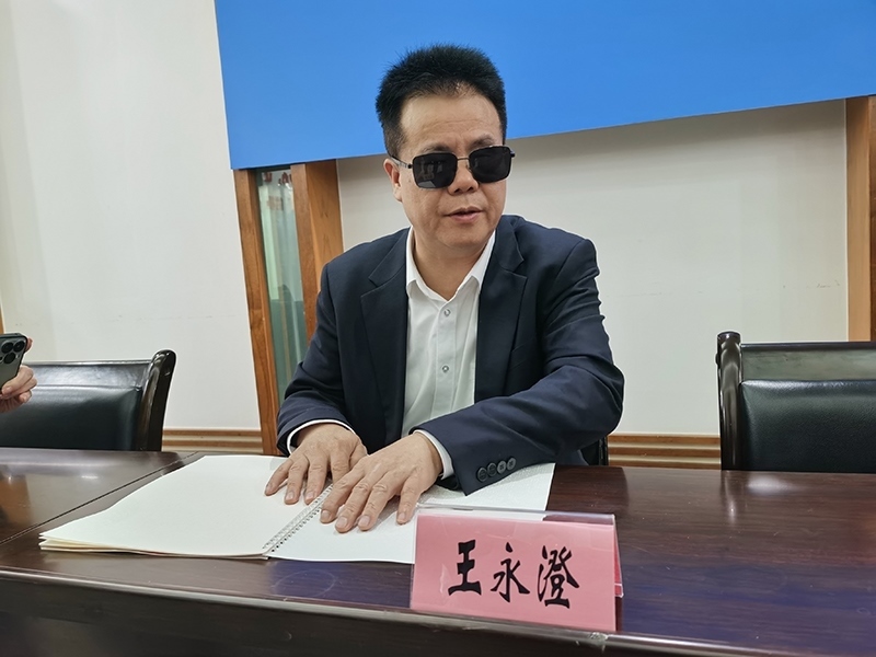 全國(guó)人大代表王永澄正在閱讀盲文版代表建議答復(fù)。本報(bào)記者 張 璁?dāng)z