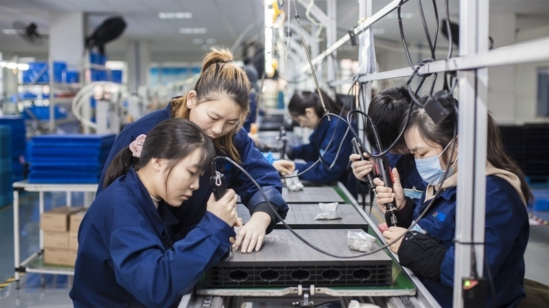 在新亞勝光電的產(chǎn)品線上，工人正進行產(chǎn)品組建和安裝布線。受訪者供圖