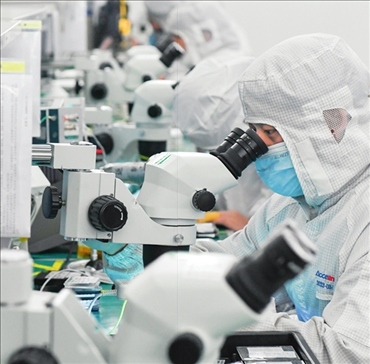 在位于武漢中國(guó)光谷的光電器件研發(fā)制造商——武漢光迅科技股份有限公司生產(chǎn)車間內(nèi)，技術(shù)人員在光模塊生產(chǎn)線作業(yè)（2023年4月11日攝）。程敏攝/本刊