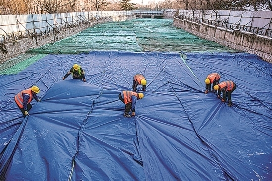 1月3日，房山區(qū)東風(fēng)街道，工人正在修復(fù)的河道內(nèi)給混凝土鋪設(shè)保溫布。