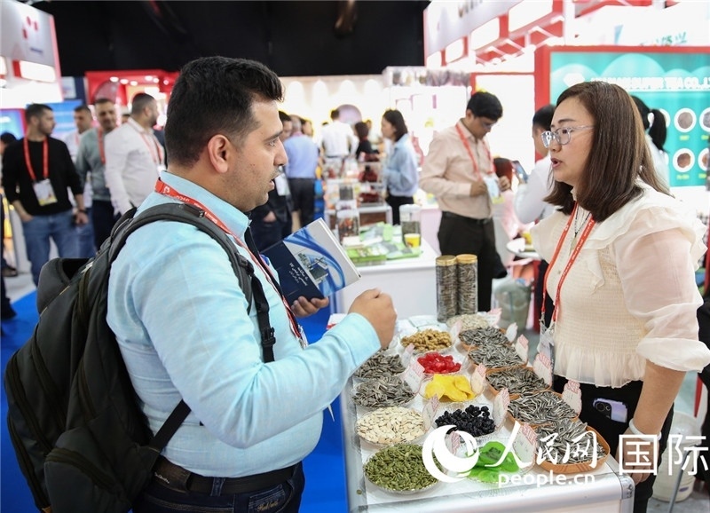 圖為一家中國干果參展企業(yè)代表與采購商洽談。人民網(wǎng) 塔里克·易卜拉欣攝