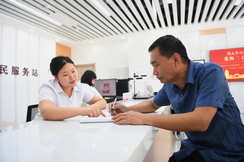 2023年5月23日，河北雄安新區(qū)容東片區(qū)南文營(yíng)社區(qū)居民（右）在社區(qū)便民服務(wù)站辦理業(yè)務(wù)。
