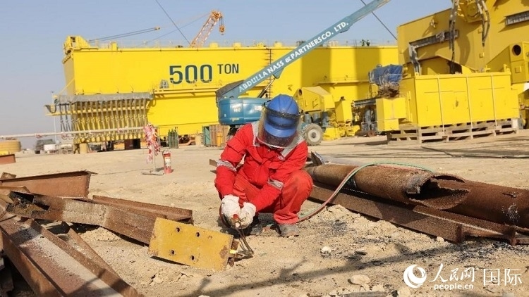 工人正在龍門吊吊裝現(xiàn)場切割金屬件。人民網(wǎng)記者管克江攝