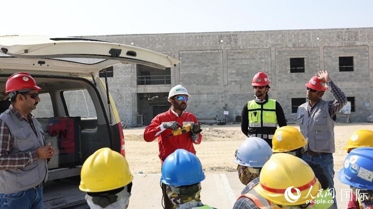 穆薩瓦爾(圖中紅衣人）現(xiàn)場演示工具操作規(guī)范。人民網(wǎng)記者 管克江攝