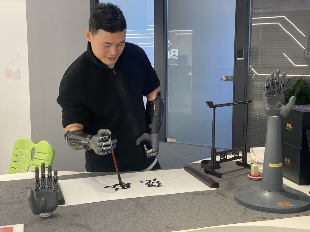 2024年3月29日，在浙江強(qiáng)腦科技有限公司展廳內(nèi)，失去雙手的產(chǎn)品體驗(yàn)官倪敏成依靠智能仿生手寫毛筆字。新華社記者 魏一駿 攝