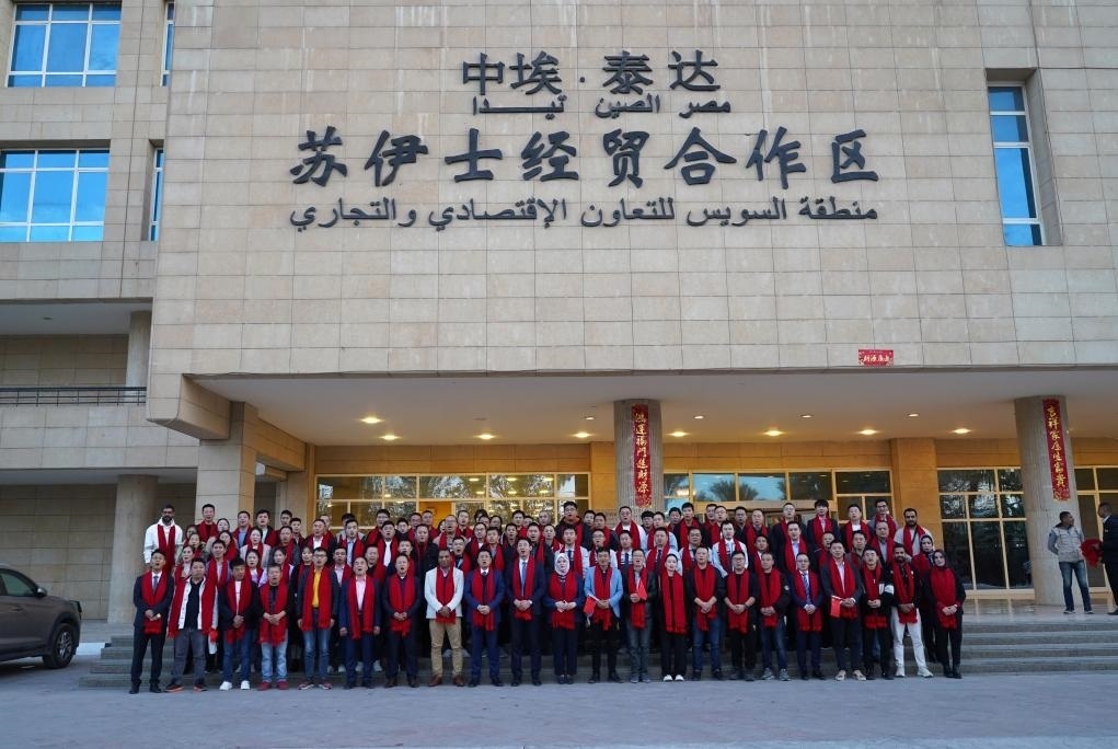 2024年2月11日，在位于埃及蘇伊士省的中?！ぬ┻_(dá)蘇伊士經(jīng)貿(mào)合作區(qū)，中埃員工在合作區(qū)辦公大樓前合影拜年。新華社發(fā)（泰達(dá)合作區(qū)供圖）