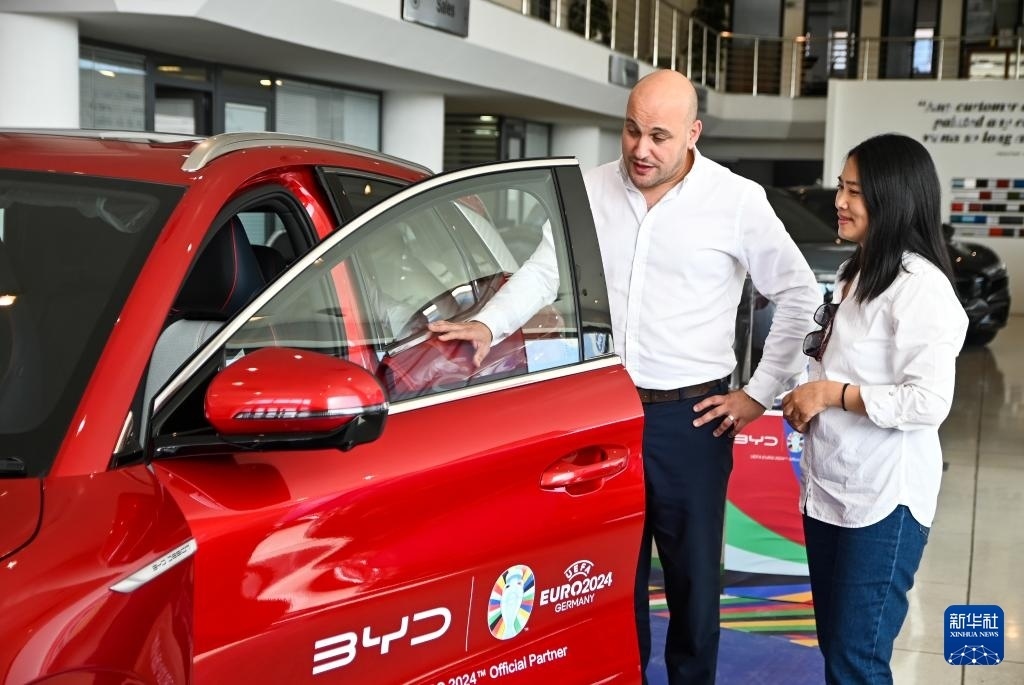 2024年5月29日，在馬耳他比爾基卡拉，馬耳他哈桑-扎米特汽車公司首席執(zhí)行官德古阿拉（左）介紹一輛比亞迪純電動(dòng)汽車。新華社發(fā)（喬納森·博格 攝）