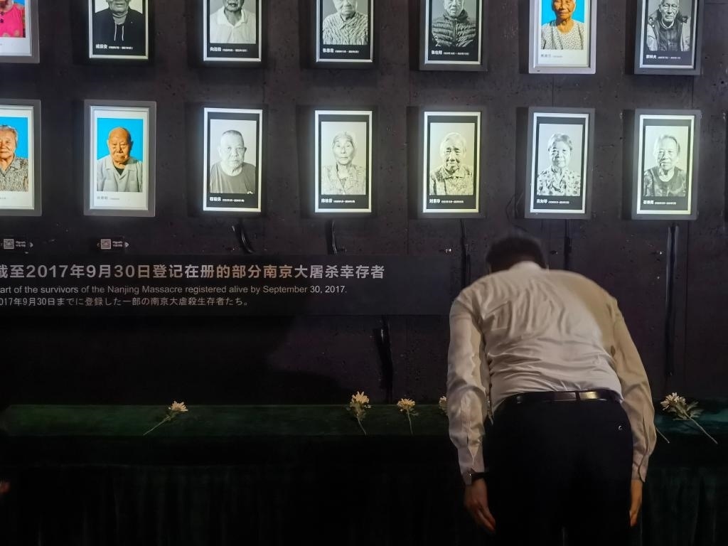 7月18日，人們向離世的南京大屠殺幸存者獻(xiàn)花、鞠躬。新華社記者邱冰清 攝