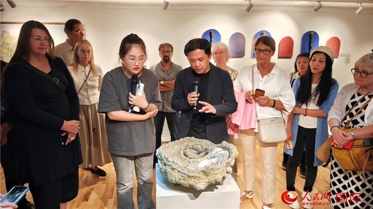 參展人、景德鎮(zhèn)陶瓷大學設(shè)計藝術(shù)學院副院長余劍峰（中）向來賓介紹參展作品。人民網(wǎng)記者 殷淼攝