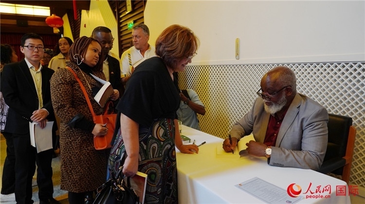 譚哲理在活動現(xiàn)場簽名贈書。人民網(wǎng) 劉暢攝