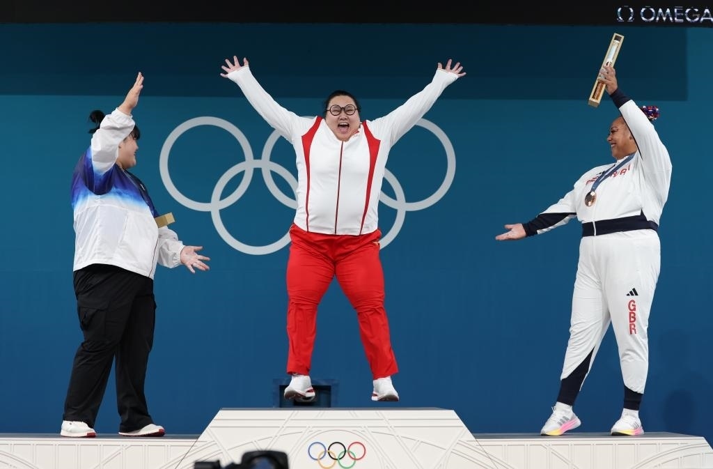 中國選手李雯雯（中）在巴黎奧運會舉重女子81公斤以上級頒獎儀式中登上領(lǐng)獎臺（2024年8月11日攝）。新華社記者 楊磊 攝