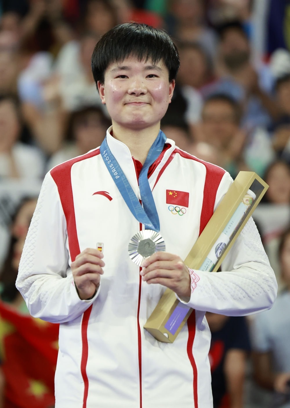 巴黎奧運會羽毛球女子單打亞軍、中國選手何冰嬌在頒獎儀式上一手握著銀牌，一手握著西班牙奧委會徽章（2024年8月5日攝）。新華社記者 任正來 攝