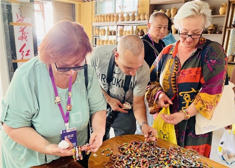 歐亞媒體考察團(tuán)成員在母氏陶藝館內(nèi)挑花了眼，色彩絢麗、質(zhì)地均勻的陶藝手串讓他們愛(ài)不釋手?！斑@里的東西都太實(shí)惠了！”塔吉克斯坦《索格特真理報(bào)》政論部主任娜塔利婭·多羅費(fèi)耶娃說(shuō)。花茂村的特色產(chǎn)品物美價(jià)廉，讓考察團(tuán)成員為家人好友買(mǎi)到了心儀的禮物，也為此次以四川成都為起點(diǎn)，路經(jīng)南充、廣安至貴州遵義的考察行程畫(huà)上了圓滿(mǎn)句號(hào)。（張亞欣攝）