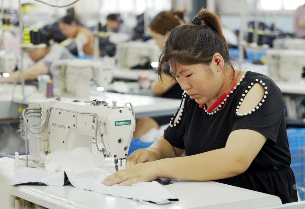 5月20日，村民在李寨村服裝加工廠內(nèi)忙碌。河南省周口市沈丘縣馮營鎮(zhèn)李寨村地處豫東平原。近年來，乘著脫貧攻堅與鄉(xiāng)村振興政策的東風，李寨村積極探索產(chǎn)業(yè)發(fā)展模式，通過“龍頭企業(yè)+村集體經(jīng)濟+農(nóng)戶”的方式，逐漸發(fā)展形成肉牛養(yǎng)殖、設(shè)施農(nóng)業(yè)、服裝加工、康養(yǎng)民宿等產(chǎn)業(yè)，以產(chǎn)業(yè)振興助力鄉(xiāng)村振興。新華社記者 李嘉南 攝