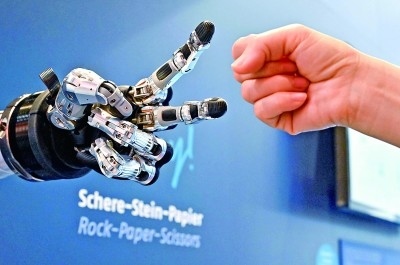 在德國漢諾威工博會上，參觀者與一款智能機器人進行“石頭剪子布”游戲。新華社發(fā)