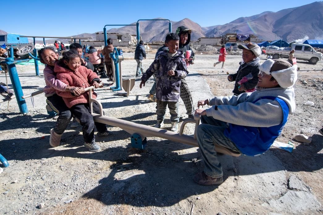 1月11日，在定日縣措果鄉(xiāng)塘仁村安置點，西藏星光社會工作服務(wù)中心志愿者和孩子們一起玩耍，進行災(zāi)后心理疏導(dǎo)。人民網(wǎng)記者 翁奇羽攝