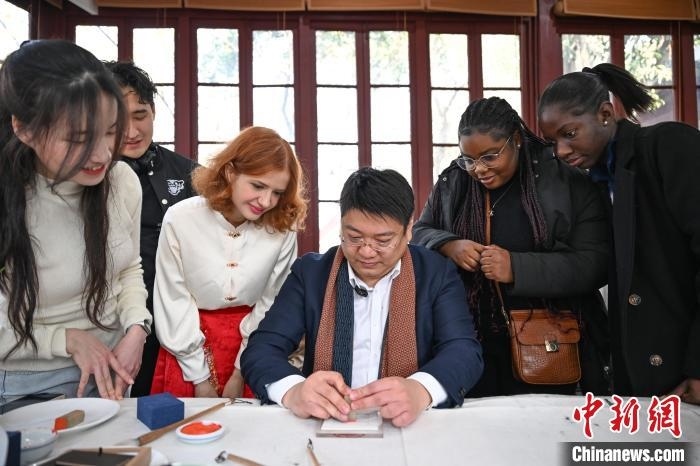 1月20日，篆刻家王臻向外籍留學生展示篆刻印章。當日，來自巴西、馬來西亞、加納、哈薩克斯坦的外籍留學生在浙江杭州西泠印社體驗福貼、春聯(lián)和篆刻，感受古老的中國傳統(tǒng)文化。中新社記者 王剛 攝