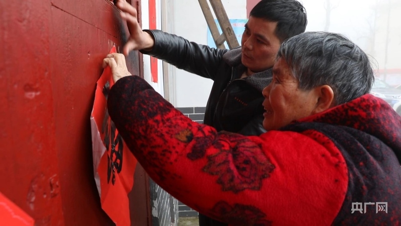 彭德良與70多歲母親貼春聯(央廣網記者 郇康新 攝)