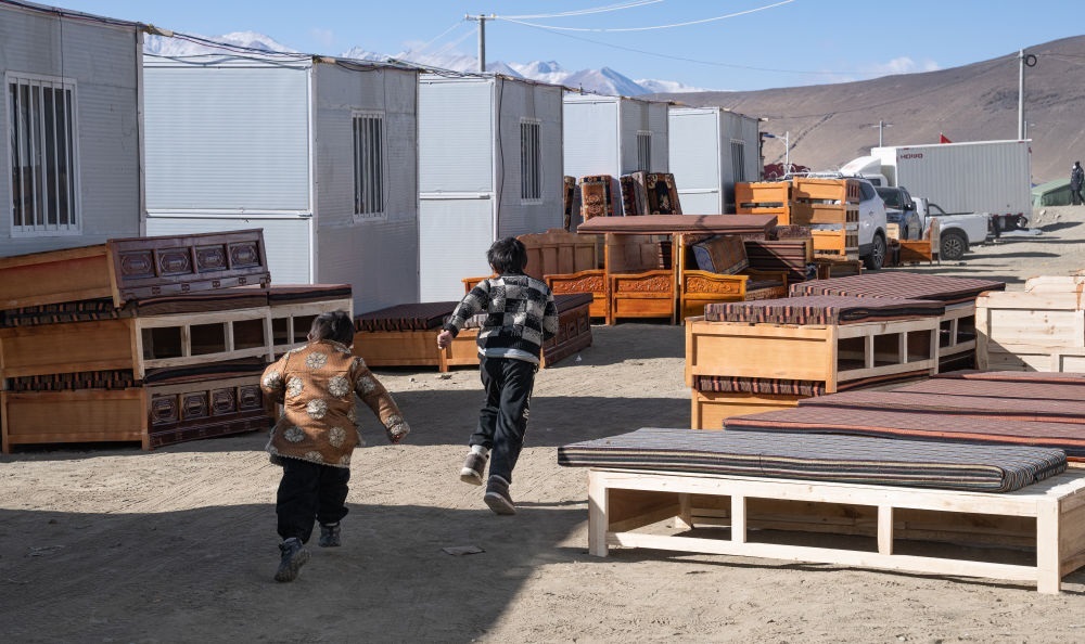 2025年1月13日，在定日縣嘎旦村，兩個孩子在剛運(yùn)來的兩排藏床間奔跑。新華社記者丁增尼達(dá) 攝