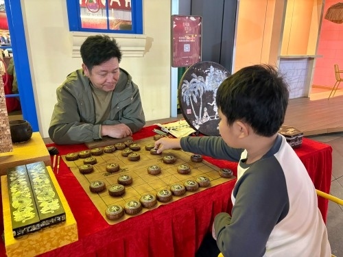 柯秋楓與市民下椰雕象棋。人民網(wǎng) 陳葉欣攝