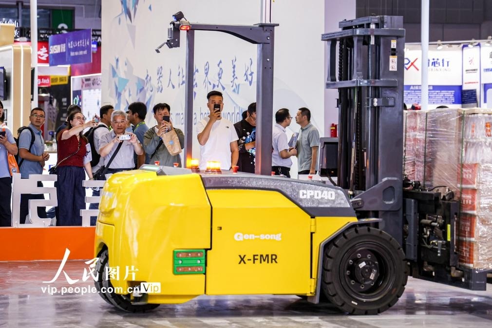 第24屆中國工博會現(xiàn)場，觀眾觀看叉取機器人作業(yè)演示。王初攝（人民圖片網(wǎng)）