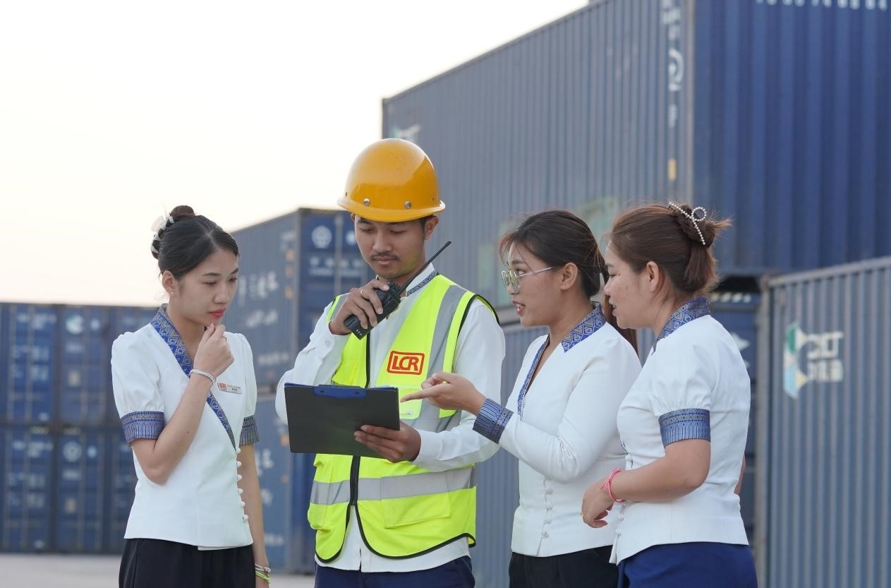 萬象南站貨運值班員陳尼啦（左一）與同事在一起討論工作。老中鐵路有限公司供圖