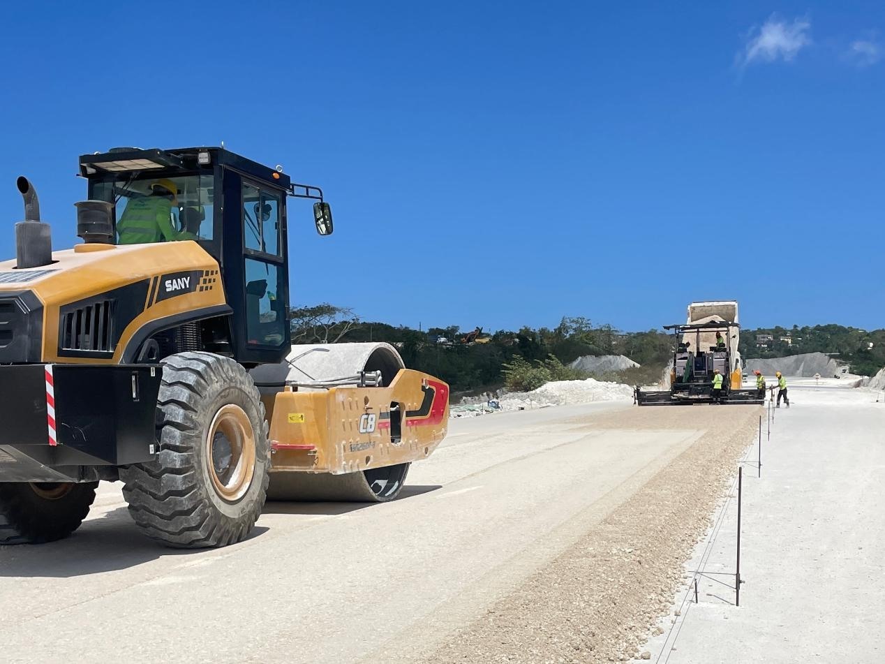 圖為中企承建的牙買加蒙特哥貝繞城路項(xiàng)目基層試驗(yàn)段正在進(jìn)行攤鋪和碾壓施工，相關(guān)施工工作已于日前順利完成。中國(guó)港灣美洲區(qū)域公司供圖