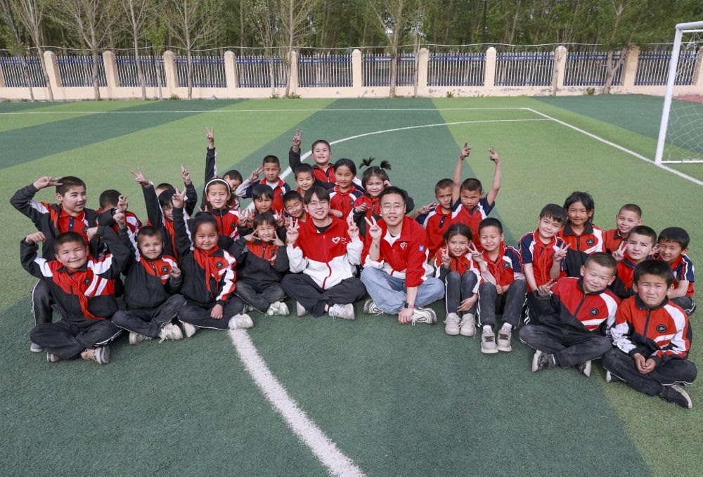 4月23日，在新疆克州阿圖什市哈拉峻鄉(xiāng)謝依特小學(xué)，支教教師王俊文（中左）、李軻凡（中右）和學(xué)生在一起。