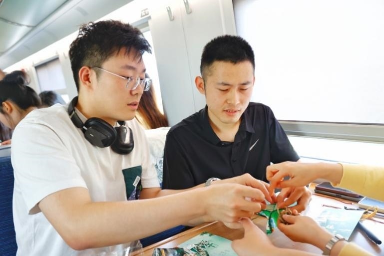 G232次旅客親手制作端午荷包和五彩繩。王磊攝