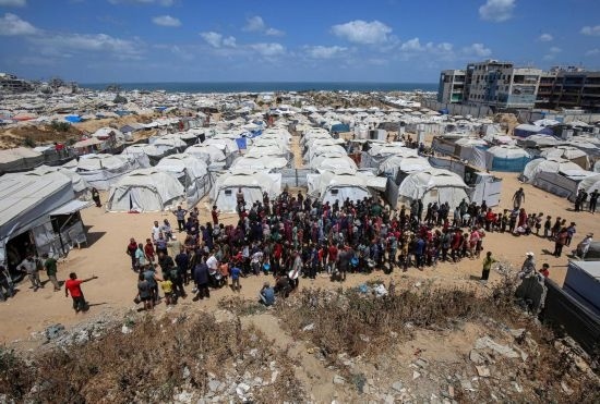 5月28日，人們在加沙城西部的沙提難民營等待領取救助食物。新華社發(fā)（里澤克·阿卜杜勒賈瓦德攝）